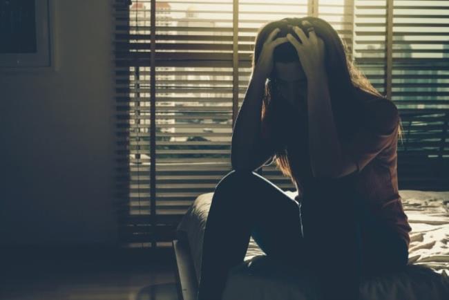 אישה מדוכאת יושבת ומחזיקה את הראש, פלובוקסאמין  לטיפול בדיכאון